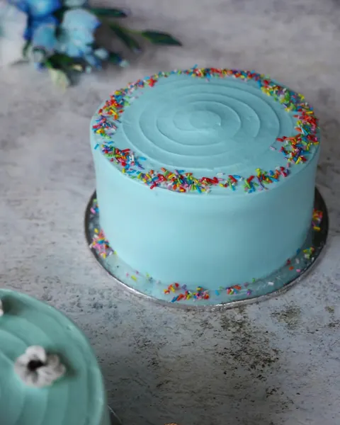 A cream cake with pastel sprinkles and piped rosettes