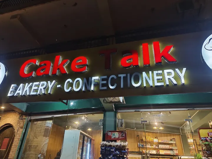 The Cake Talk shopfront at night, its sign lit in red and white